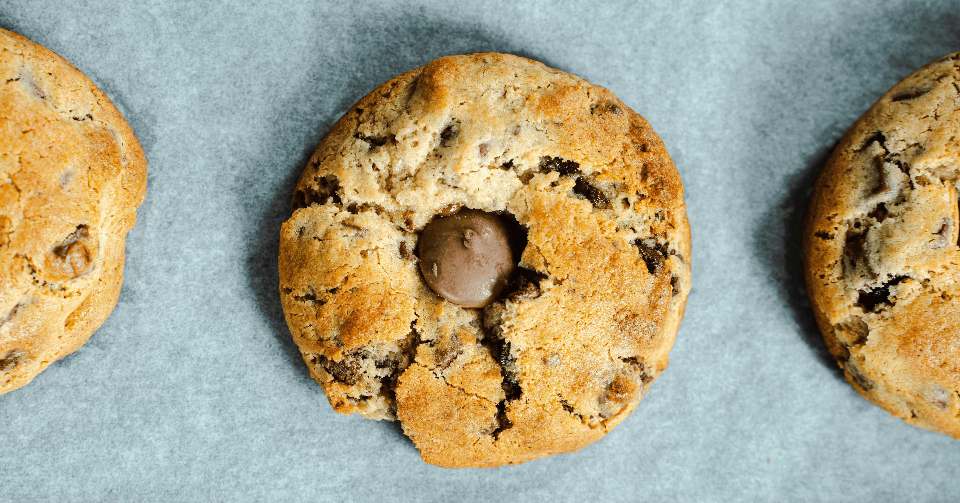 Chocolate chip cookies lined up on a grey surface